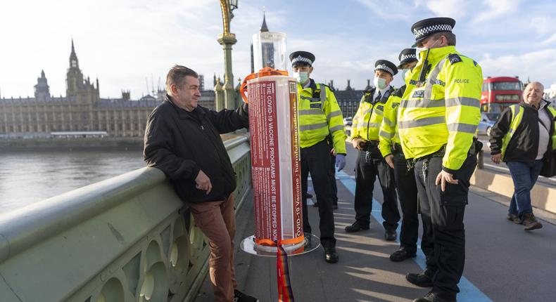 A protester with a model Covid 19 vaccine syringe is detained by police officers at a demonstration against a COVID-19 vaccine education event in London, United Kingdom on November 24, 2020.
