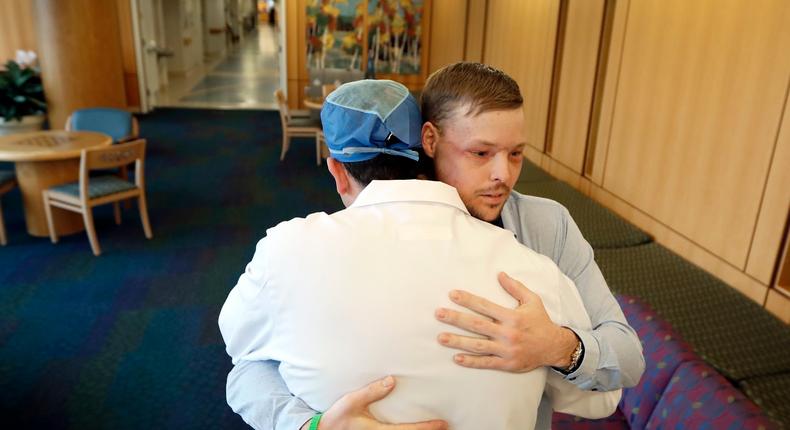 In this Jan. 25, 2017, photo, face transplant recipient Andy Sandness is hugged by Dr. Samir Mardini, foreground, during a visit to the Saint Marys Hospital campus at the Mayo Clinic in Rochester, Minn. Mardini led a medical team to perform Sandness' face transplant surgery, the first performed at the medical center.