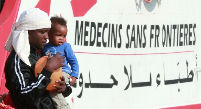 A migrant man carries a child as they disembark from the Italian rescue ship Vos Prudence run by NGO Medecins Sans Frontieres (MSF) as it arrives in the early morning of July 14, 2017, in the port of Salerno carrying 935 migrants, including 16 children and 7 pregnant women rescued from the Mediterranean sea.