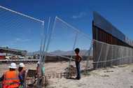 File photo of a boy looking at U.S. workers building a section of the U.S.-Mexico border wall at Sun