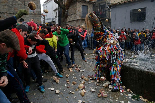 Revellers throw turnips at the Jarramplas, a character who wears a devil-like mask and a colourful c