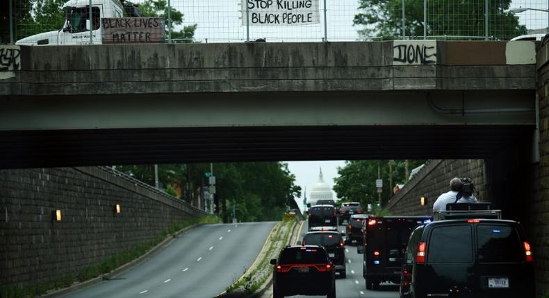 Protesters display signs over President Donald Trump's motorcade in Washington, DC
