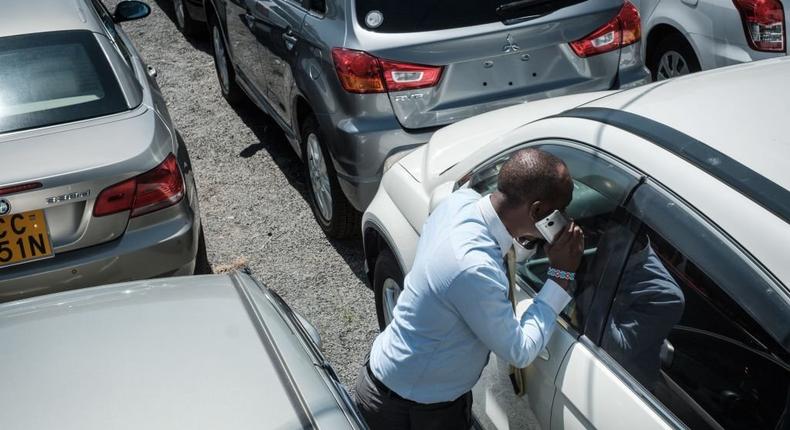 A customer checks inside a car at a used car shop on October 4, 2017 in Nairobi.  (Photo by YASUYOSHI CHIBA/AFP via Getty Images)