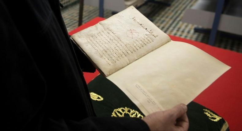 A man reads a manuscript on astronomy by renowned tenth century Muslim philosopher Al-Farabi, at the al-Qarawyin Library on November 21, 2016