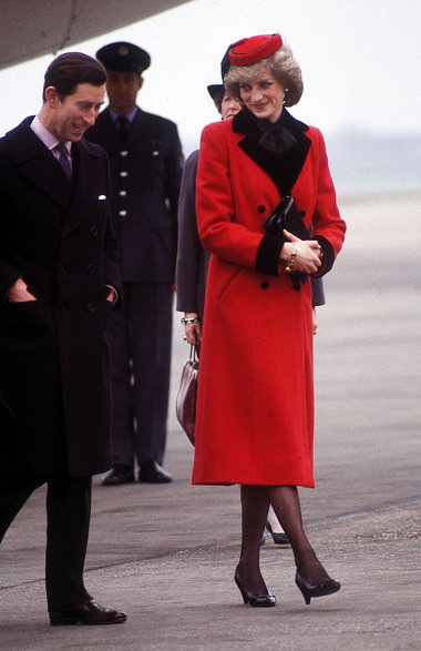Księżna Diana i książę Karol na lotnisku w 1984 r. Lady Di tego dnia miała czerwony płaszcz Catherine Walker.
