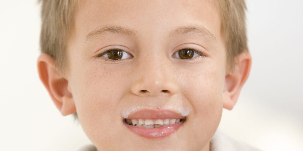 Young boy indoors drinking milk smiling