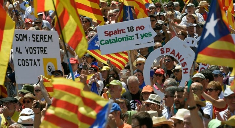 People wave flags and hold up placards during a demonstration dubbed, Referendum is Democracy organized by the ANC, AMI and Omnium Cultural, in Barcelona on June 11, 2017 in favour of Catalonia breaking away from Spain