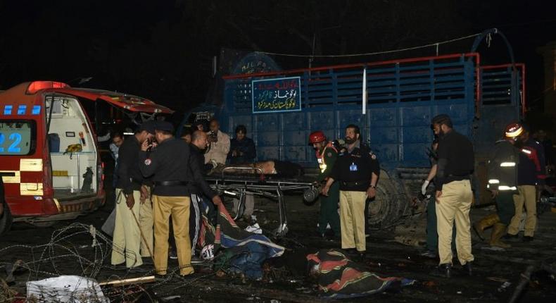 Pakistani policemen and volunteers move the bodies of victims at the site of a bomb explosion in Lahore on February 13, 2017