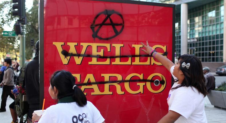 Protestors run by a defaced sign at a Wells Fargo Bank during Occupy Oakland's general strike on November 2, 2011 in Oakland, California.
