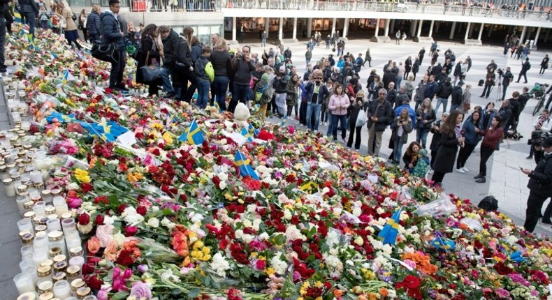 People place flowers on April 9, 2017 on the steps at Sergels Torg plaza in Stockholm close to the point where a truck drove into a department store in Stockholm, Sweden