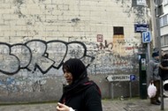 A woman passes close to the house where Salah Abdeslam was arrested after a shootout with police in 