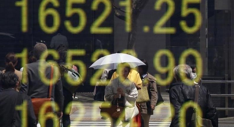 A woman clad in a kimono is reflected in an electronic board displaying Japan's Nikkei share average outside a brokerage in Tokyo, Japan, April 18, 2016. 