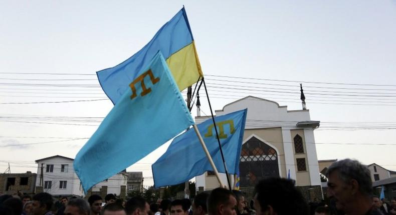 Crimean Tatars hold Ukrainian and Tatar flags at a memorial ceremony marking the 70th anniversary of the deportation of Tatars from Crimea, near a Mosque in Simferopol on May 17, 2014