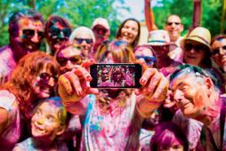 People taking a selfie together in group during a Holi celebration party in the outdoor with happiness expressions and covered with vivid colors.