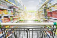 Supermarket aisle with empty green shopping cart