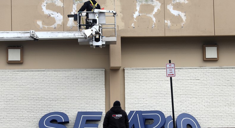 Workers remove a sign from the outside of a Sears department store in Nanuet, New York.Reuters