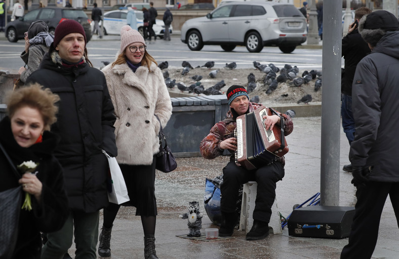 Bezrobotny Rosjanin gra na akordeonie na ulicy