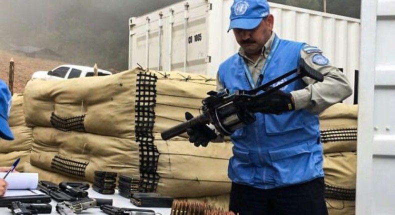 Handout picture released by the United Nations showing a member of the UN international observers' mission in Colombia holding a weapon surrendered by the Revolutionary Armed Forces of Colombia (FARC) as part of the peace process