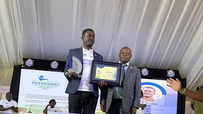 Ssentogo posing with his award. Besides him is the Iganga District Resident Judge, Justice David Batema