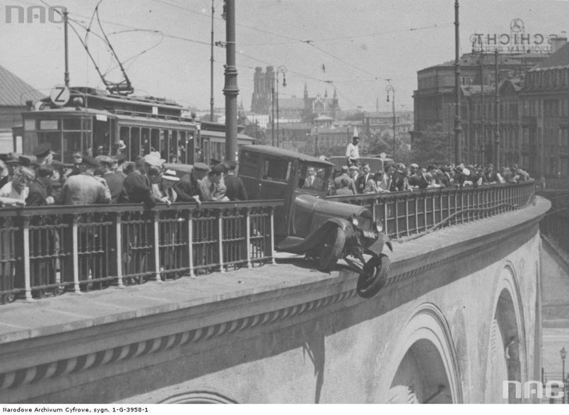 Samochód ciężarowy, który wyłamał barierkę na wiadukcie Pancera na Nowym Zjeździe w Warszawie. Widoczni gapie obserwujący akcję ratunkową i tramwaj linii "Z". W tle kościół św. Floriana i św. Michała Archanioła na Pradze, 7 lipca 1938 r. źródło: Narodowe Archiwum Cyfrowe