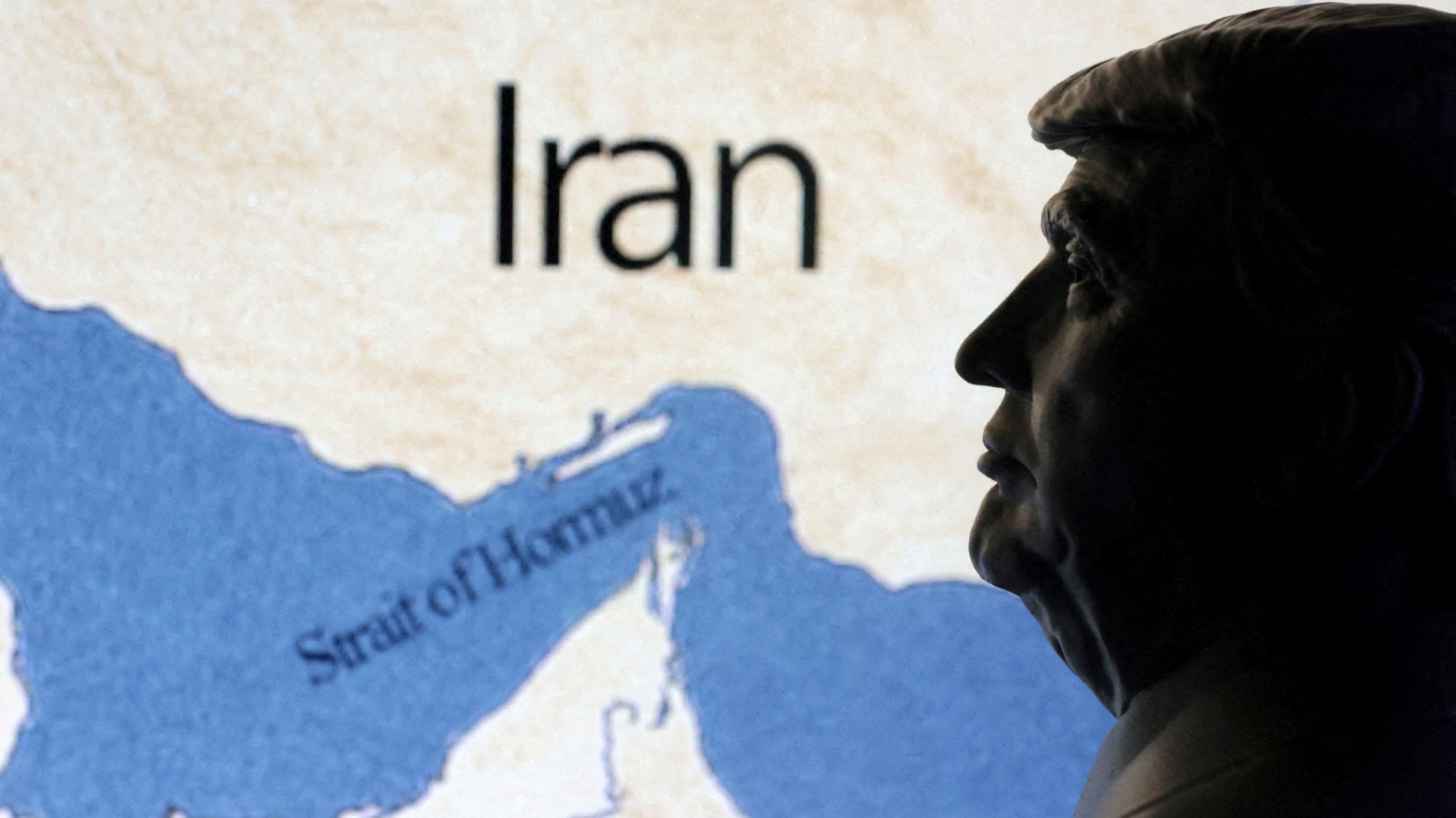 Mapa zobrazujúca Hormuzský prieliv a Irán je viditeľná za 3D vytlačenou miniatúrou amerického prezidenta Donalda Trumpa.