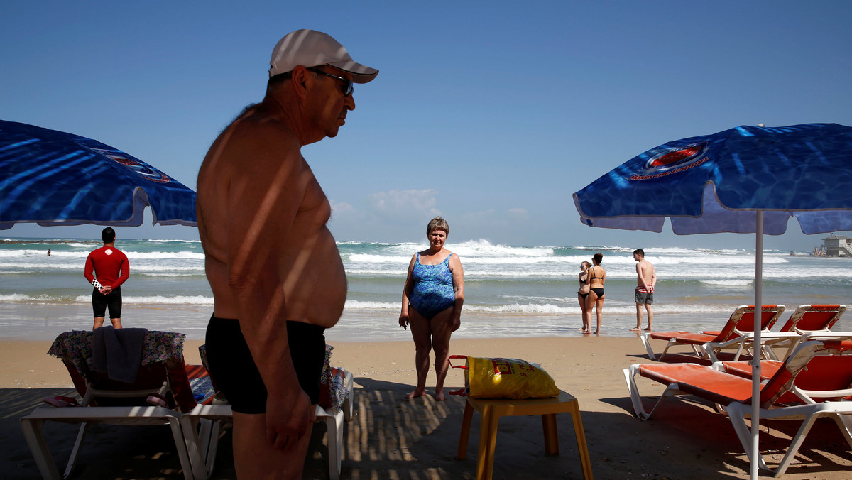 Beach-goers stand still as a two-minute siren marking annual Holocaust Remembrance Day in Israel is sounded in Netanya, Israel