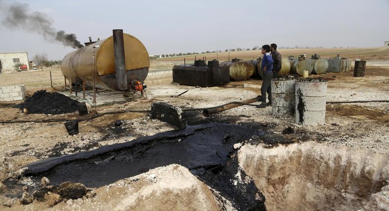 Men work at a makeshift oil refinery in Marchmarin town, southern countryside of Idlib, Syria, December 16, 2015.