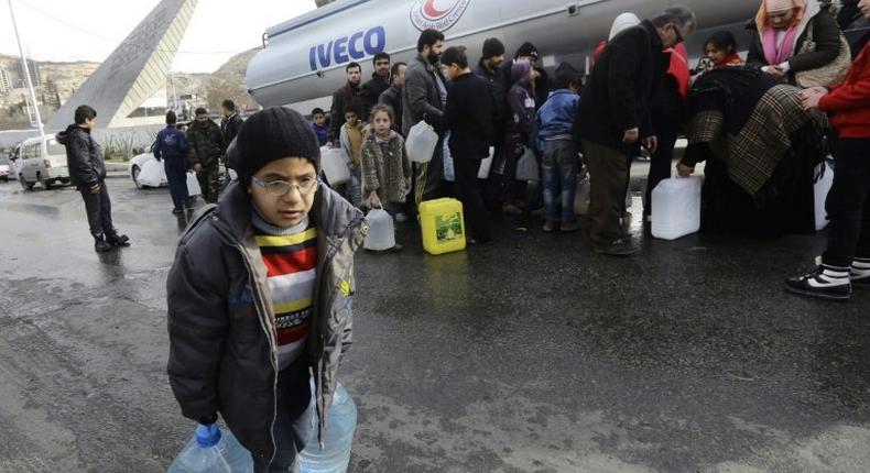 Syrians wait to fill plastic containers with water provided by the Syrian Arab Red Crescent in the capital Damascus on January 10, 2017