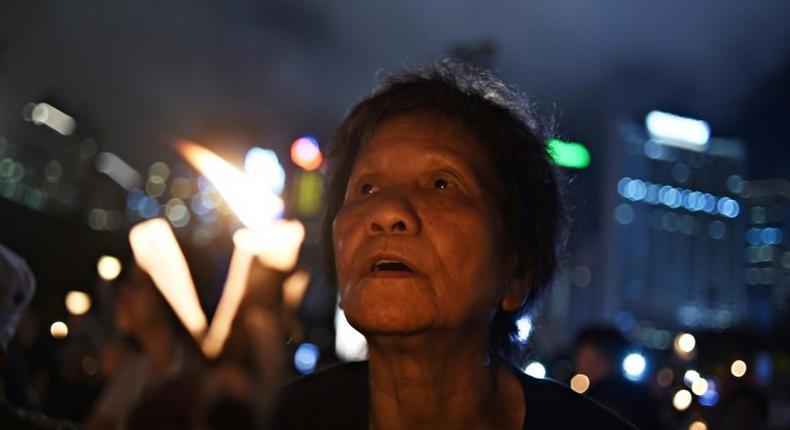 An elderly participant holds a candle with others as they attend a candlelight vigil at Hong Kong's Victoria Park on June 4, 2017, to mark the 28th anniversary of the 1989 Tiananmen crackdown in Beijing