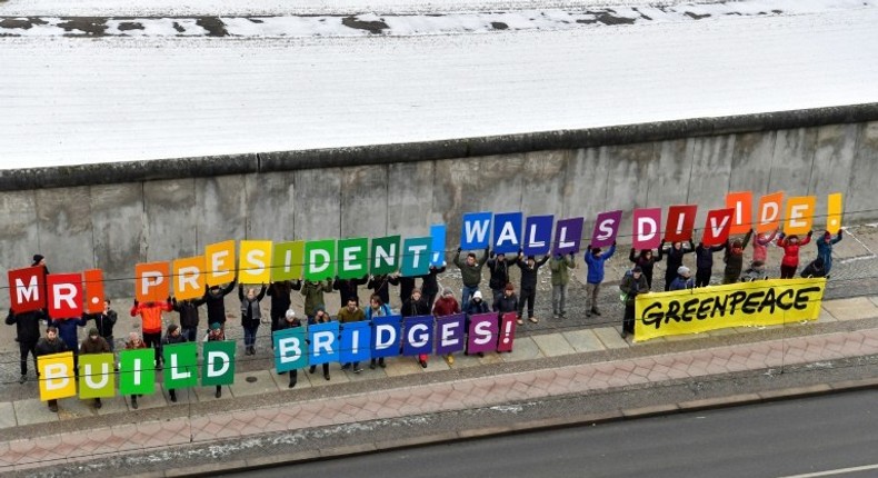 Activists from Greenpeace display a message reading Mr President, walls divide. Build Bridges! along the Berlin wall in Berlin on January 20, 2017 to coincide with the inauguration of Donald Trump as the 45th president of the United States