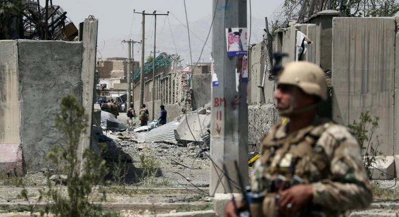 An Afghan security personnel stands guard at the site where a Taliban car bomb detonated at the entrance of a police station in Kabul on August 7