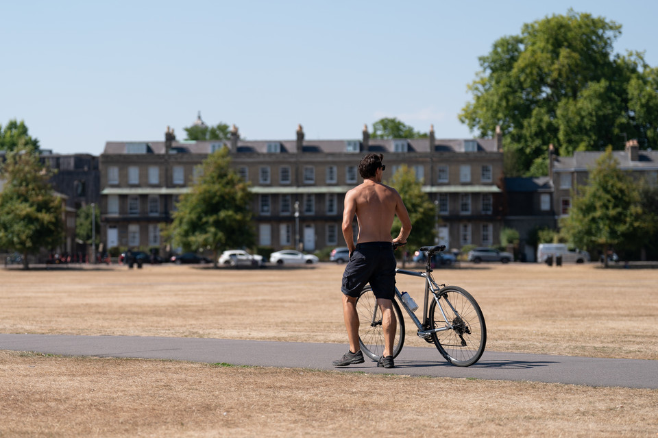 Mężczyzna pchający rower wzdłuż Parker's Piece w Cambridge