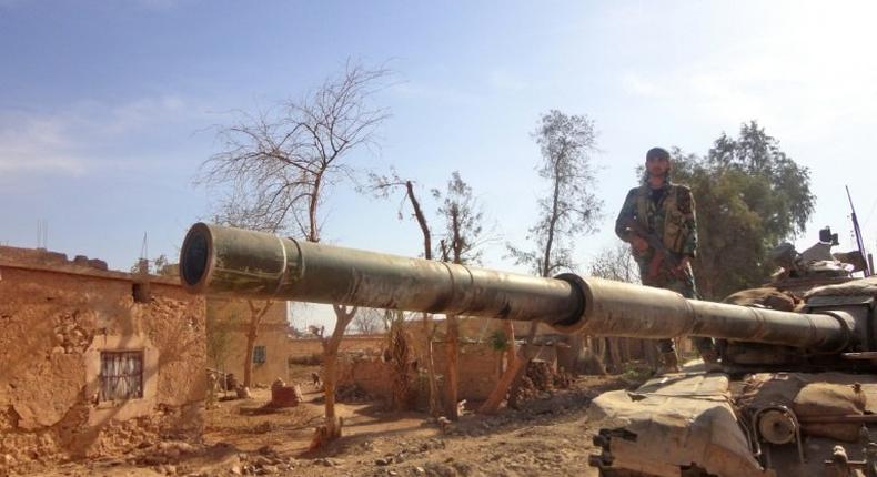 A Syrian army soldier stands atop a tank in the town of Houwayqa, in Deir Ezzor, which is almost totally under IS control