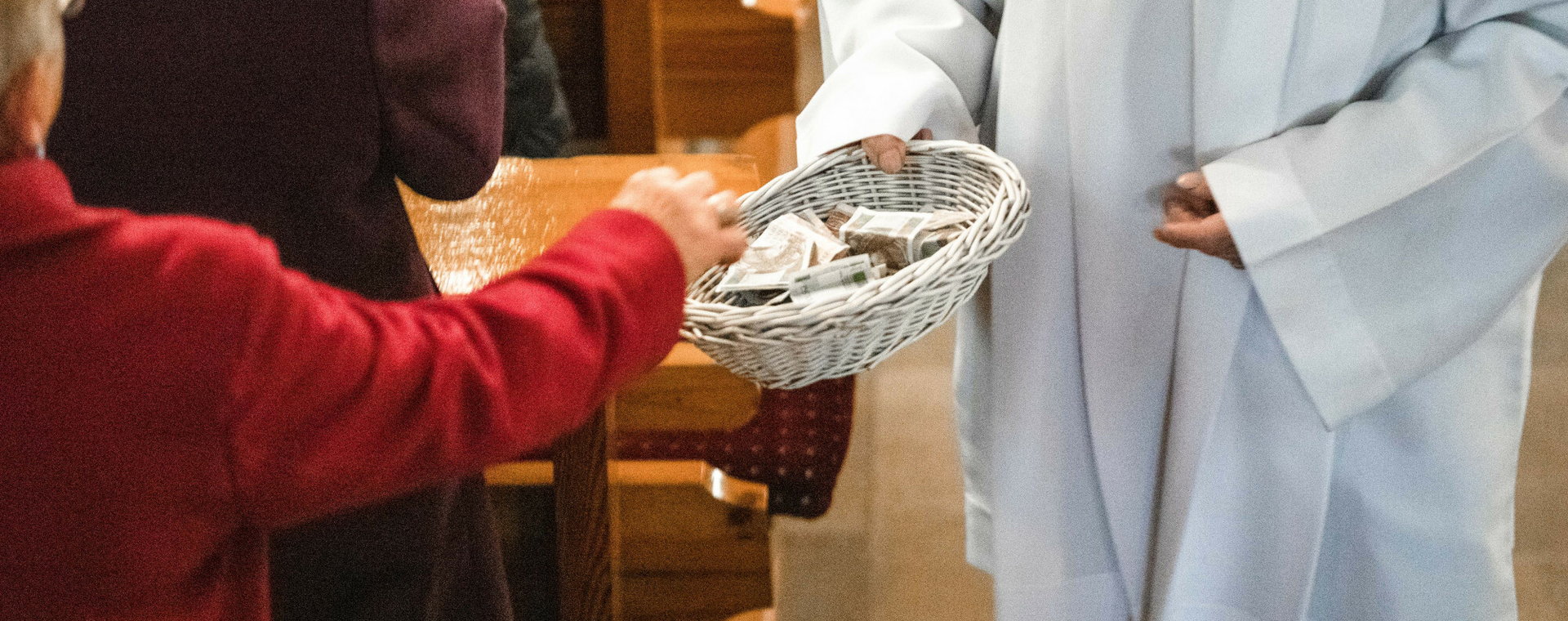 (Zdjęcie ilustracyjne) Kościelny zbiera pieniądze na tacę.