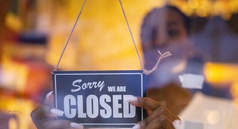 Woman puts a closed sign on glass front door of a coffee shop.Luis Alvarez/Getty Images