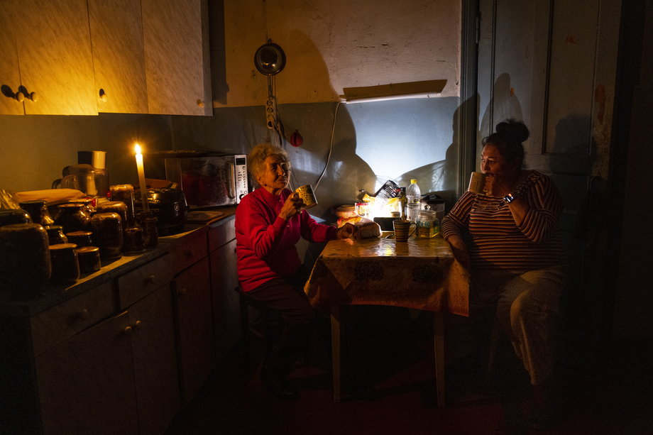 81-letnia Natalia Zemko (po lewej) rozmawia ze swoją córką Lesią Zemko, gdy piją herbatę w kuchni podczas przerwy w dostawie prądu w centrum Kijowa, 22 października 2022 r. 