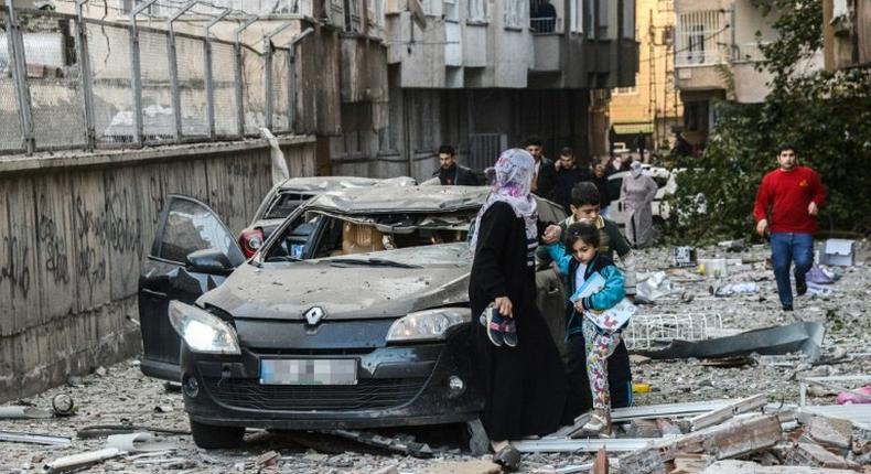 Women and children walk away from a damaged building at the site of an explosion in Diyarbakir, southeast Turkey on November 4, 2016