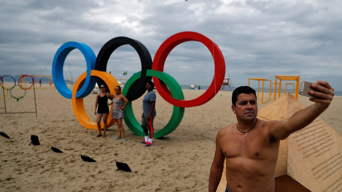 Man takes a selfie in front of the Olympic Rings, displayed at the Copacabana beach ahead of the 201