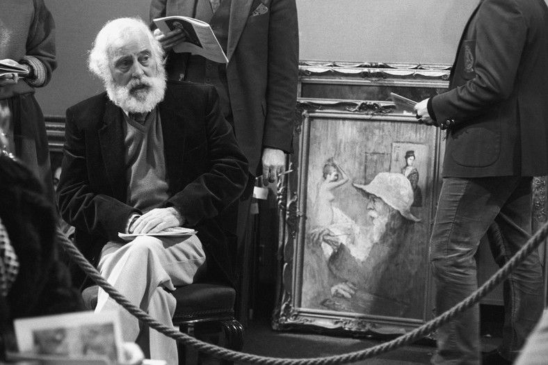 Tom Keating siedzi obok swojego autoportretu w sali aukcyjnej londyńskiej Christie's [1983]