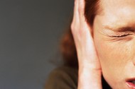 Young woman squinting eye closed, hand covering ear, close-up