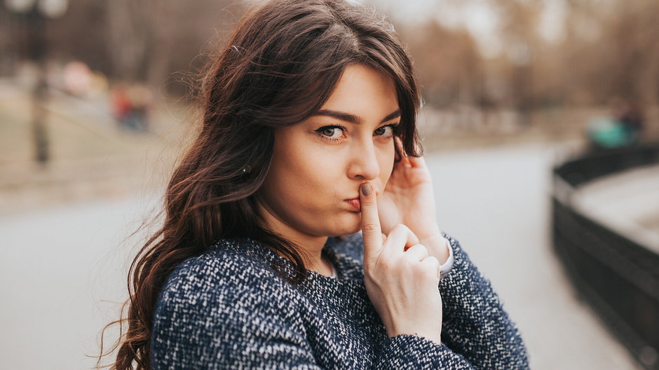 Closeup portrait secretive young woman placing finger on lips