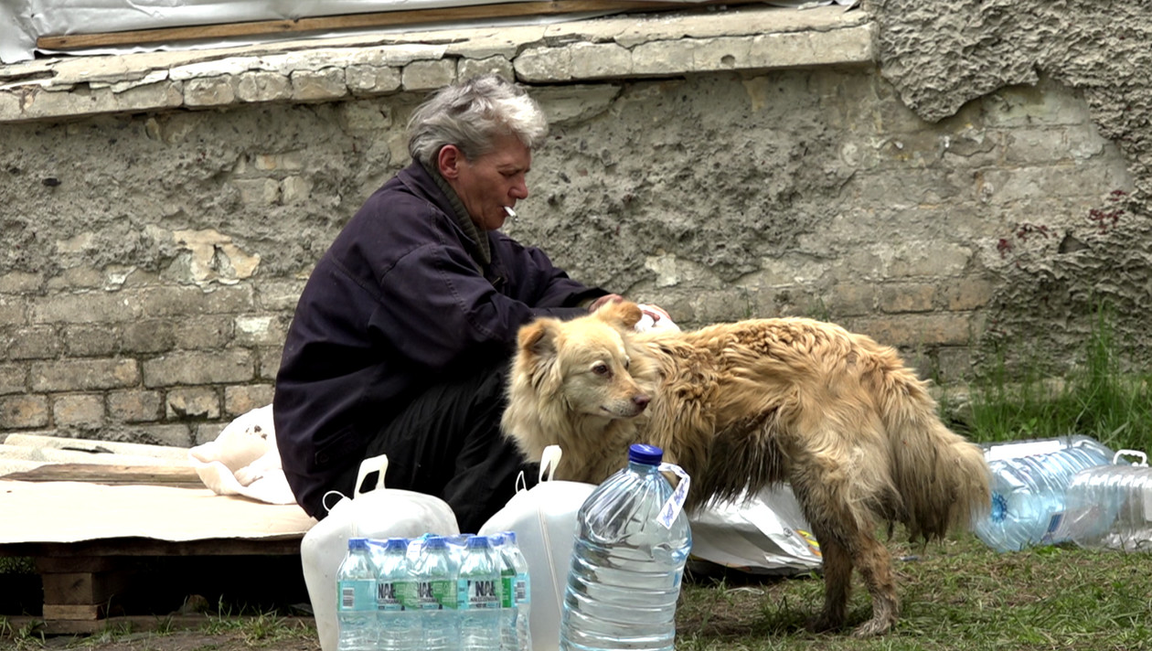 Mieszkanka Czasiw Jaru z psem w punkcie dystrybucji wody.