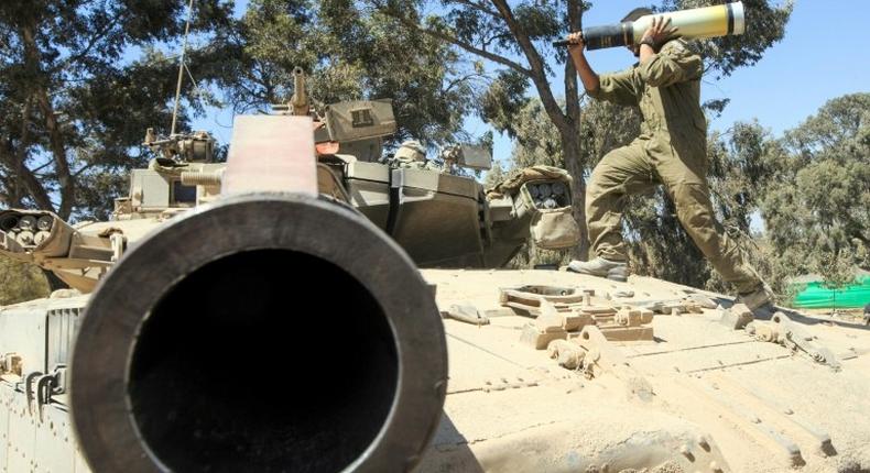 An Israeli soldier carries a shell as he and his comrades prepare their Merkava tanks stationed on the border between Israel and the Gaza Strip on July 31, 2014