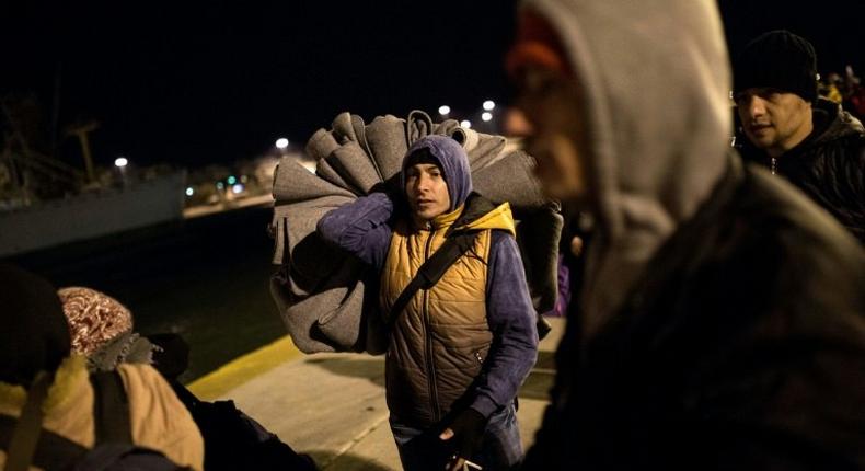 Refugees and migrants disembark from a passenger ferry, with many presenting registration papers stating that Germany or Austria is their final destination, on January 23, 2016