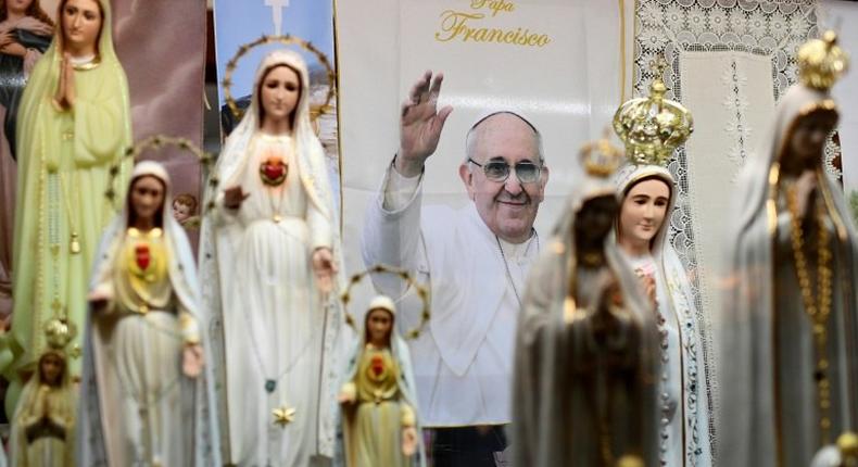 A poster depicts Pope Francis among statues of Our Lady of Fatima in a window shop of souvenirs in Fatima, central Portugal, ahead of his visit