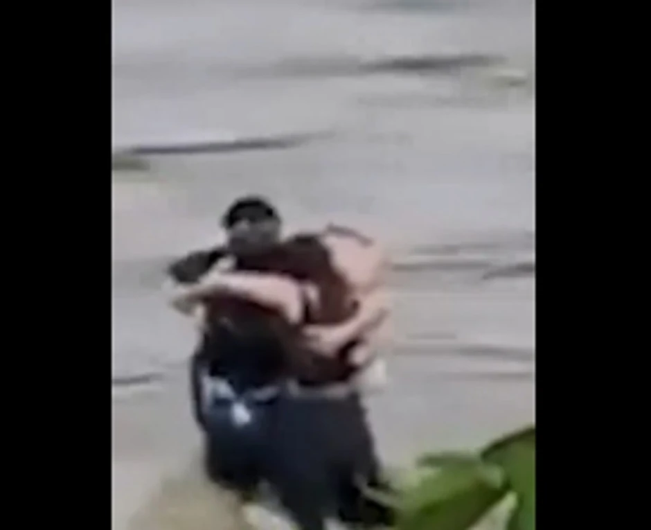 Troje mladih stoje zagrljeni u sred bujice u Udinama, Italija