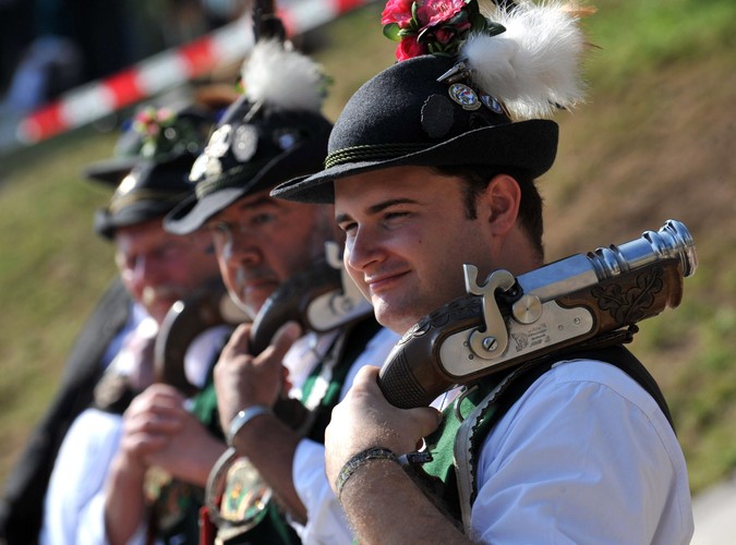 Mężczyźni ubrani w tradycyjne stroje szykują się na oddanie salwy oznajmiającej koniec Oktoberfest