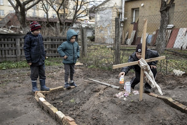 Wojna w Ukrainie. Dzieci na grobie matki zabitej w Buczy i pochowanej na podwórku domu