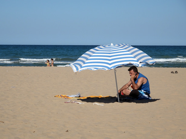 Mężczyzna na plaży rozmawiający przez telefon