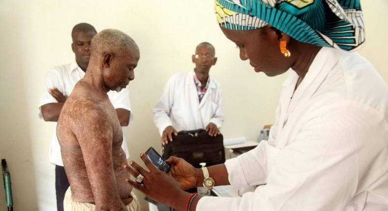 A doctor takes pictures of a man's skin condition for diagnosis through an online dermatology platform in Mali